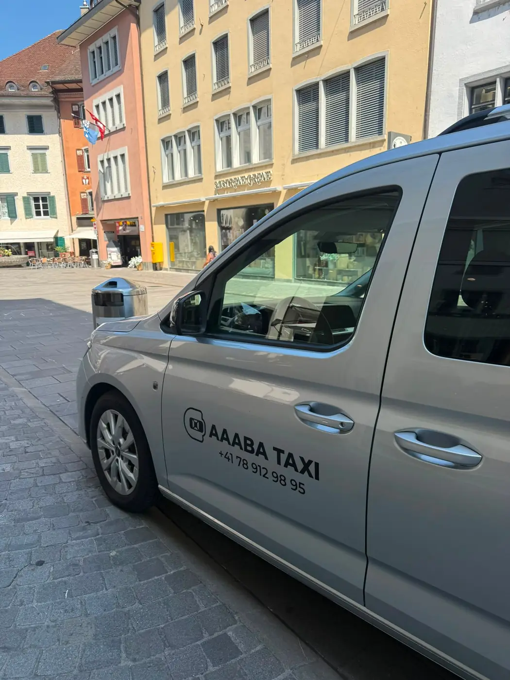 Silbernes Rollstuhlfahrzeug von Aaaba Taxi auf der Strasse