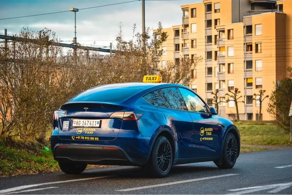 Blaues Tesla Model Y von Aaaba Taxi in der Heckansicht